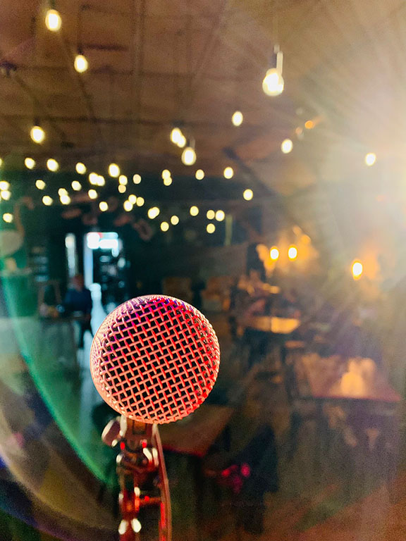 Nahaufnahme eines Mikrofons mit stimmungsvoller Lichtkulisse – Atmosphäre vor dem Auftritt